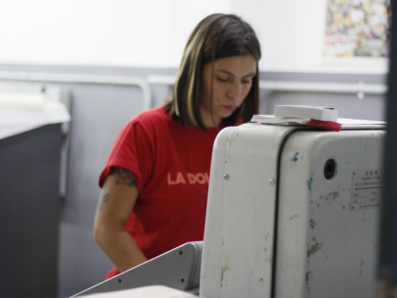Trabajadora de la cooperativa operando la guillotina del taller